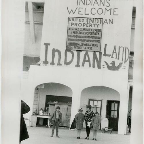 People posing for photo in front of Building 64 with "Indians welcome" and Indian Land" painted above the entrance