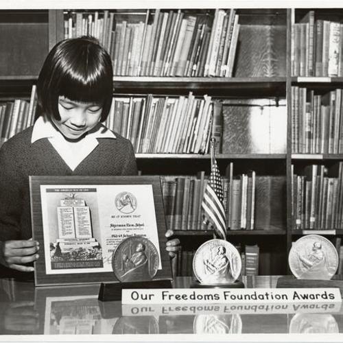[Student from Sherman Elementary School holding a certificate awarded to the school]