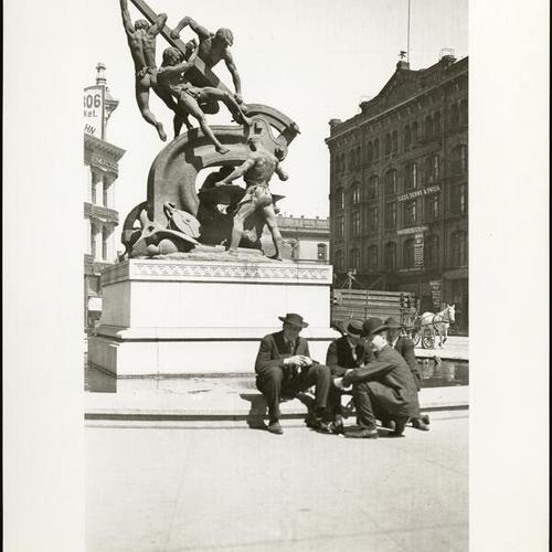[Four men sitting in front of the Donahue Monument, also known as the Mechanics Monument, on Market Street]