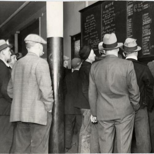 [Group of longshoremen looking at an announcement board in a Longshoremen's Dispatching Hall]