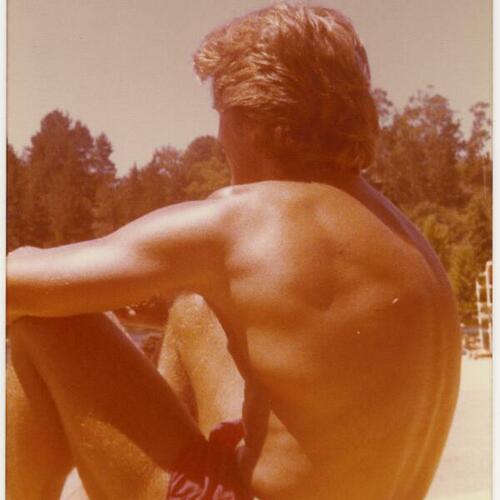 David Kopay in swimwear sitting near the water's edge at Lake Tahoe