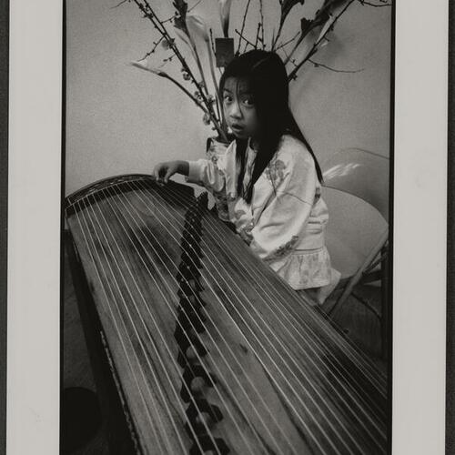 Child playing guzheng instrument as part of Hotel and Restaurant Employees Union's Chinese New Year celebration