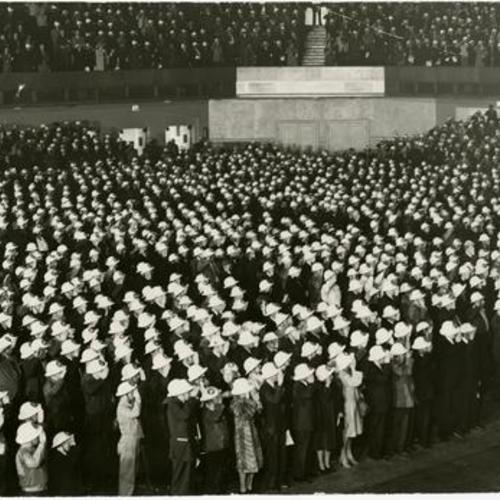 full house salutes during an air raid preparation meeting in San Francisco's Civic Auditorium]