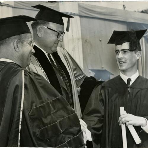 [Governor Edmund G. Brown congratulating Edmund G. Brown Jr. (Jerry) on receiving his diploma at University of California's Memorial Stadium]
