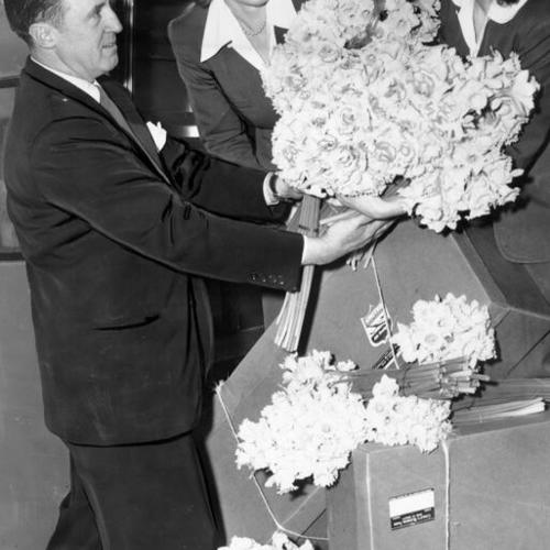 [Art Bell, Maiden Lane florist, Louise Cutter and Dorothy Johnstone holding up a large bouquet of daffodils]