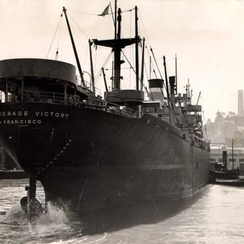[Tug boat pushing the S. S. Anchorage Victory into place alongside a San Francisco pier]