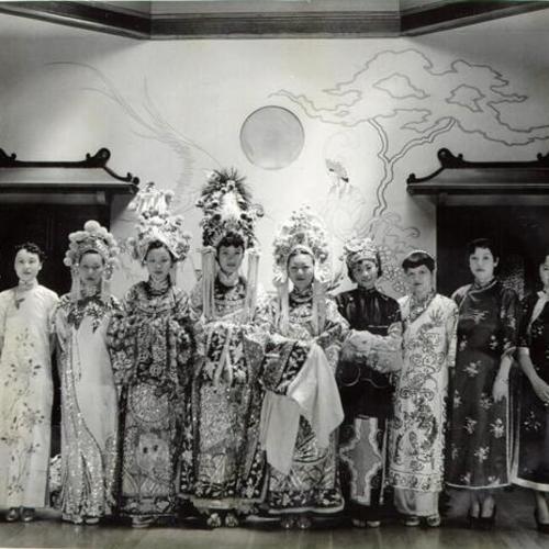 [Chinatown belles standing together on a stage dressed in the colorful garb of Old China]