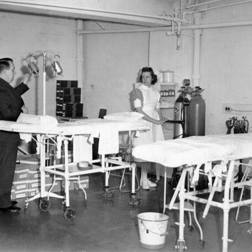 [Dr. A. J. J. Rourke, superintendent, and nurse Eve Anderson checking equipment in a bombproof emergency operating room at Stanford Hospital]