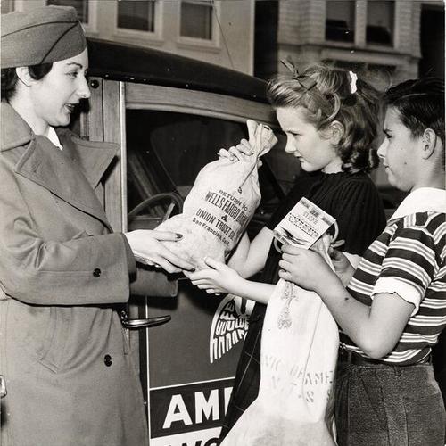 [Mary Beth Fowler of American Women's Voluntary Services (AWVS) collecting the War Bonds and Stamps money from Marlene Haghe and Ronald Abend]