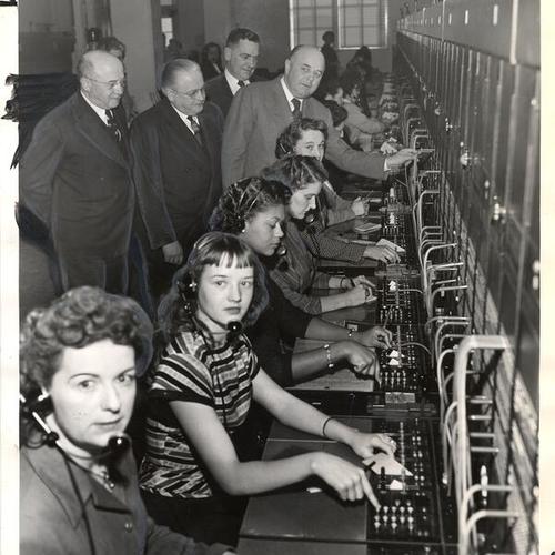 [Mayor Elmer Robinson and several Pacific Telephone and Telegraph Company executives inspecting switchboard in telephone building at 25th and Capp streets]