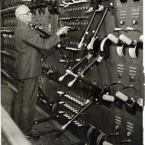[Master electrician Charles Holzmueller standing next to the electrical switchboard at the War Memorial Opera House]
