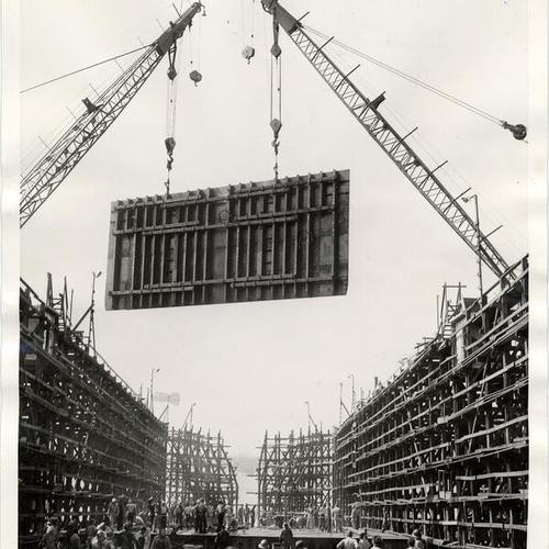 [25-ton steel bulkhead being lowered by cranes]