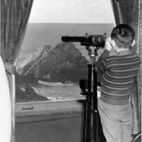 [Boy looking through telescope from Cliff House]
