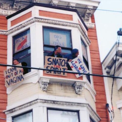 [Men holding signs out of building window in support of Dyke March in 2001 on 16th Street]