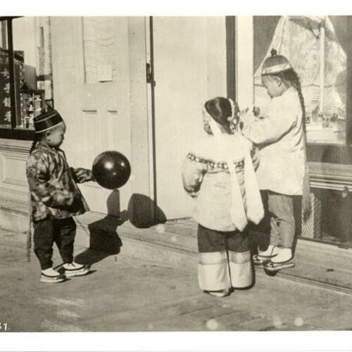 [Three young children playing outside a store in Chinatown]