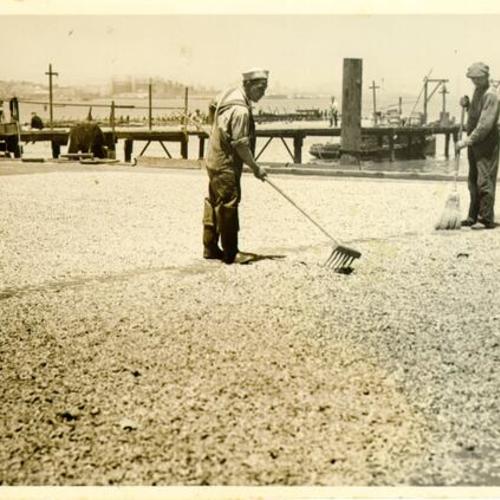 [Two people sweeping near docks in Visitacion Valley]