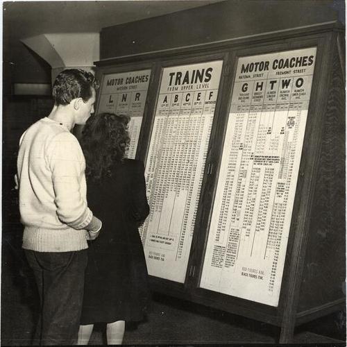[Two people looking at train schedules at Key System terminal]