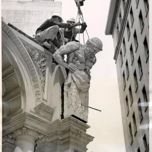 [Workmen removing a molded torso of a Greek mythological figure from the  exterior of the American Trust Company]
