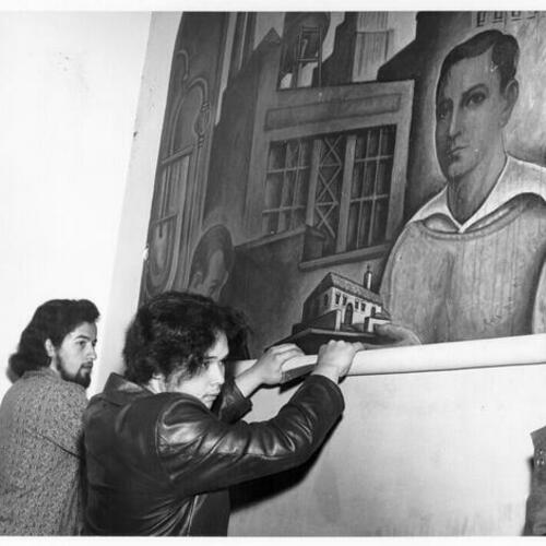 [Students removing a mural from a wall at Mission High School]
