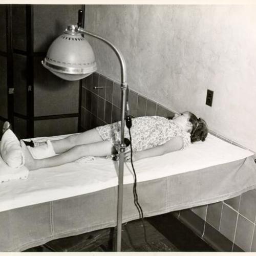 [Unidentified student lying on an examining table at Sunshine Orthopedic School]