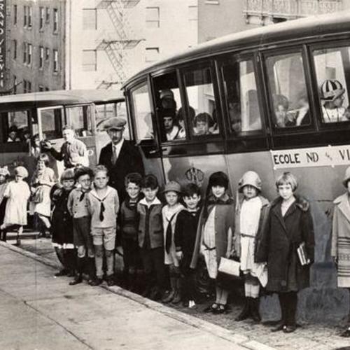 [Students of Notre Dame des Victories standing in front of the school's buses]