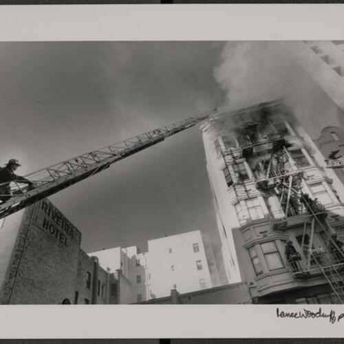 Firefighters climbing aerial ladder to reach upper floors of 376 Ellis Street during fire
