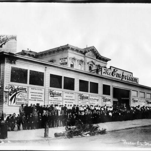 [Group photo of employees outside relocated Emporium department store at Van Ness Avenue and Post Street]