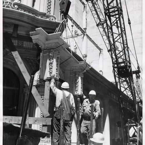 [Workmen lowering a big section of all cast iron building]