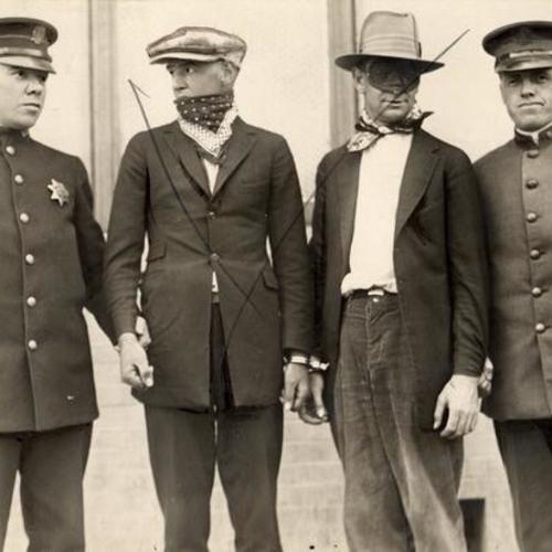 [Officers Carl Wennerberg and T.G. Kelly with two detained men in the center]