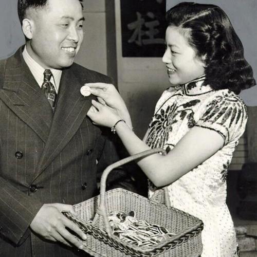 [T.Y. Tang buying a Chinese souvenir button from Patrician Joe]