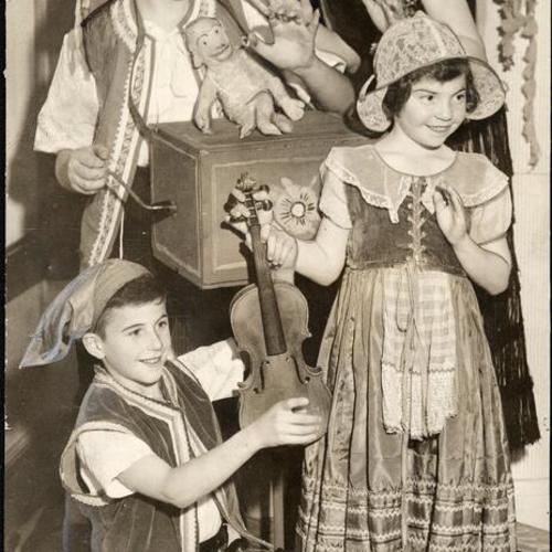 [Students Albert Landi, Adrienne Levitt, Frank Marynelli and Marie Louise McPherson of Winfield Scott Elementary dressed in costumes holding instruments]