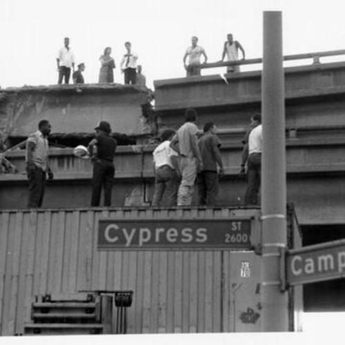 [Crowd of people standing at the site of the collapsed Cypress Street Viaduct after the October 17th, 1989 Loma Prieta earthquake]