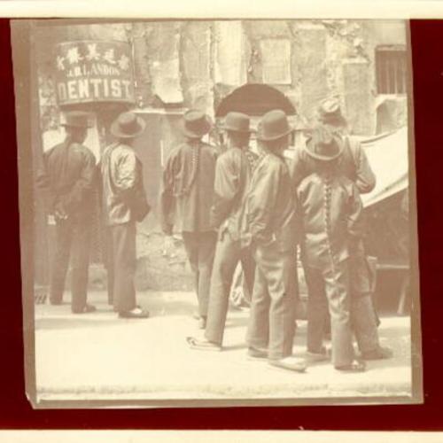 [Group of people standing outside the office of dentist J. B. Landon in Chinatown]