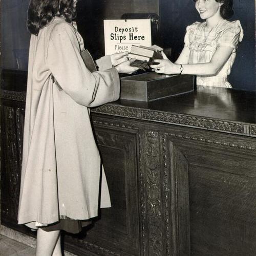 [Librarian Clare Pope handing patron Mary June King books that she requested at the Main Library]
