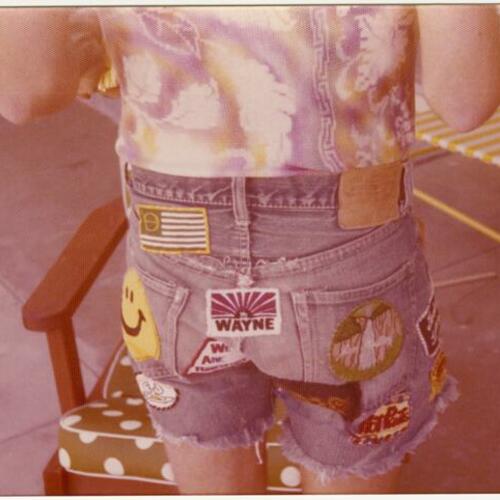 Backside of Gary wearing jeans shorts with patches standing in front of chair, Palm Springs