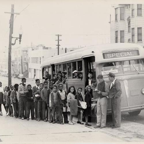 [Group of children getting on a school bus to go to day camp]