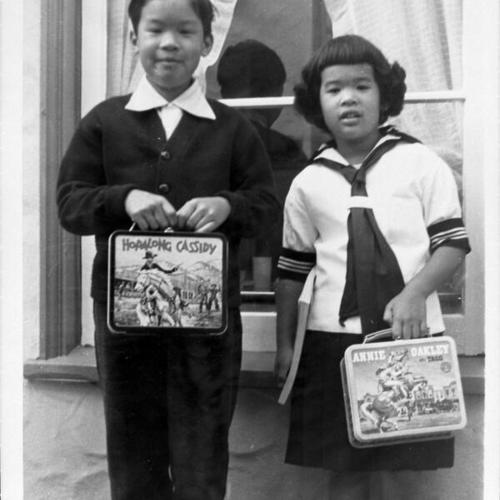 [Bob and Melinda's first day of school holding Hopalong Cassidy and Annie Oakley lunch boxes]