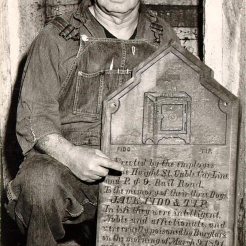 [John Nolan holding a plaque erected by employees of the Haight Street Cable Car Line in memory of their three dogs, Jack, Fido and Tip]