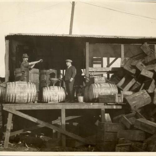 [Two men using the community grape press located near the waterfront]
