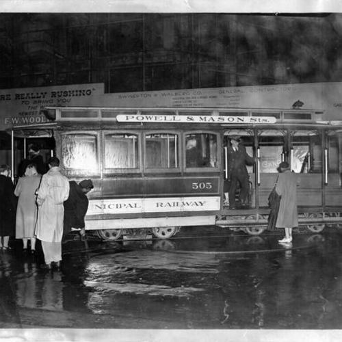 [Passengers boarding Powell Street cable car on rainy night]