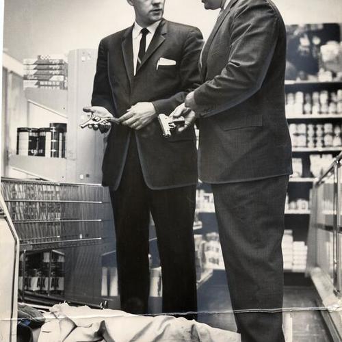 [Police Sergeant Mortimer McInerney and homicide Inspector George Asdrubale examining the pistols used during a grocery store robbery while suspect Howard Oliver Gaines lies on floor]