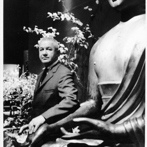 [Richard B. Gump, President of Gump's Inc., standing next to Buddha statue]