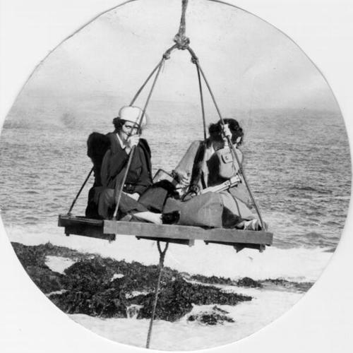 [Passengers being hoisted from a sling and boom onto an island in the Farallones]