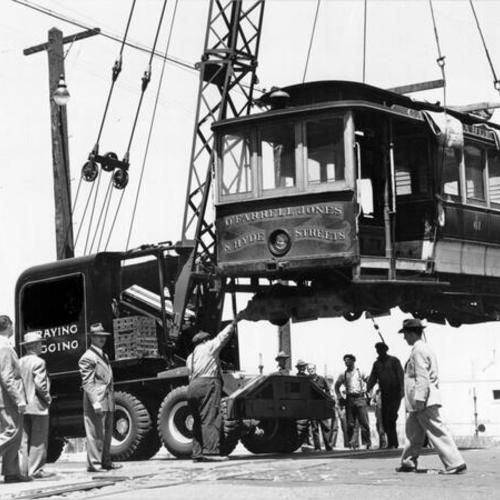 [Cable car being hoisted aboard a freight car]
