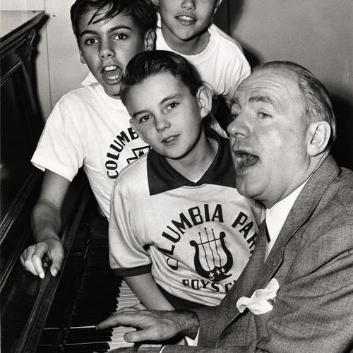 [Choir boys (back to front) Michael O'Neill, Robert O'Neill and Peter Young from the Columbia Park Boys Club with Pat O'Brien of the Strike a Match company rehearsing Christmas in Killarney]