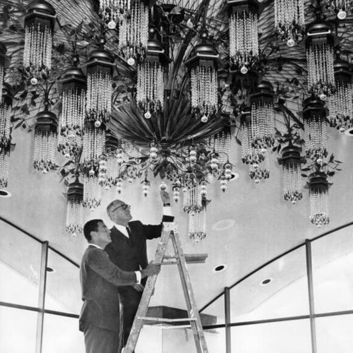[Mario Gaidano and Richard L. Swig examining the chandelier in the Fairmont Hotel Towers Pavilion room]