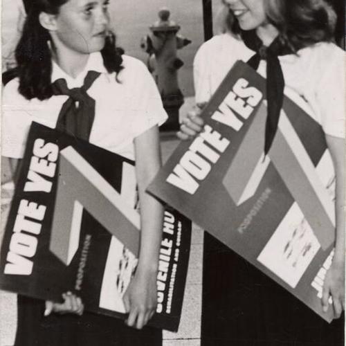 [Camp Fire Girls Gayle Hughes and Carol Thompson carrying 'Vote YES 7' posters]