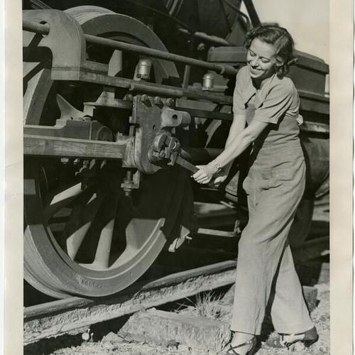 [Unidentified woman with a wrench making an adjustment to a railroad car]