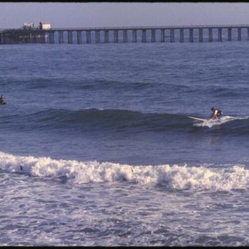People surfing near pier