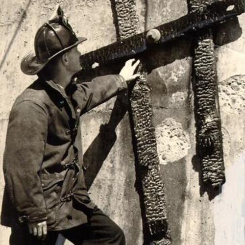 [Fireman inspecting a ladder that was burned in a fire on the cantilever span of the San Francisco-Oakland Bay Bridge]